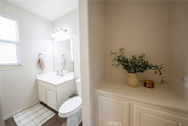 half bathroom with baseboards, vanity, toilet, and tile patterned floors