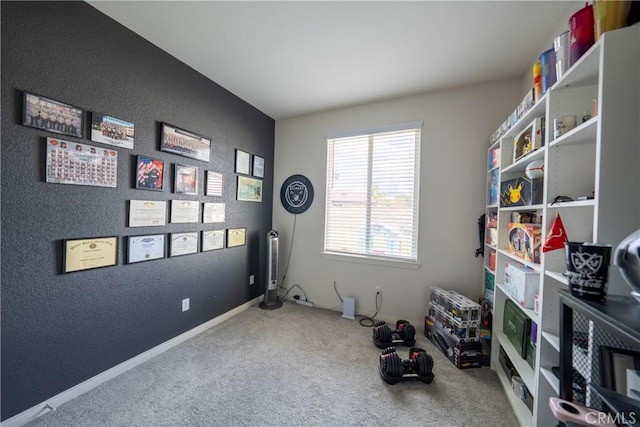 interior space with carpet floors, a textured wall, and baseboards