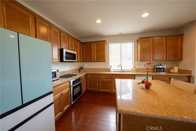 kitchen with appliances with stainless steel finishes, dark wood-type flooring, a sink, and recessed lighting