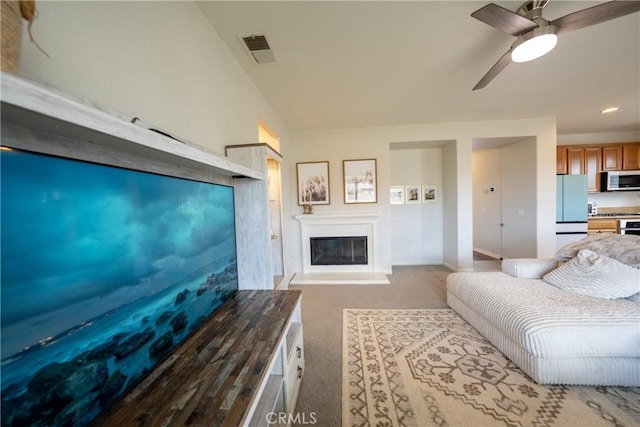 carpeted living area with ceiling fan, a glass covered fireplace, visible vents, and baseboards