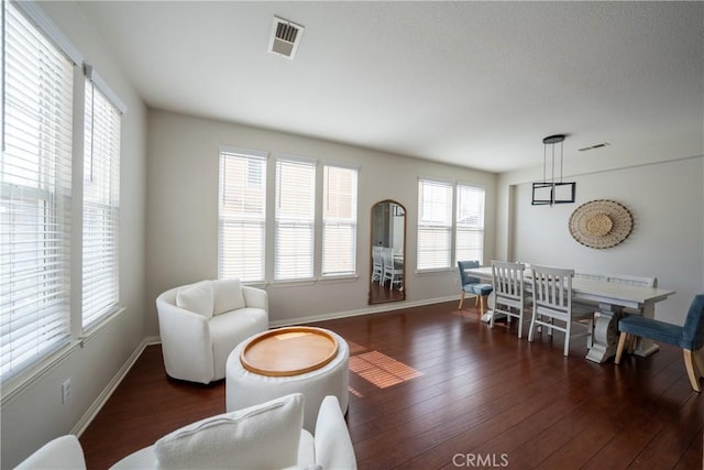 living area with hardwood / wood-style flooring, visible vents, and baseboards