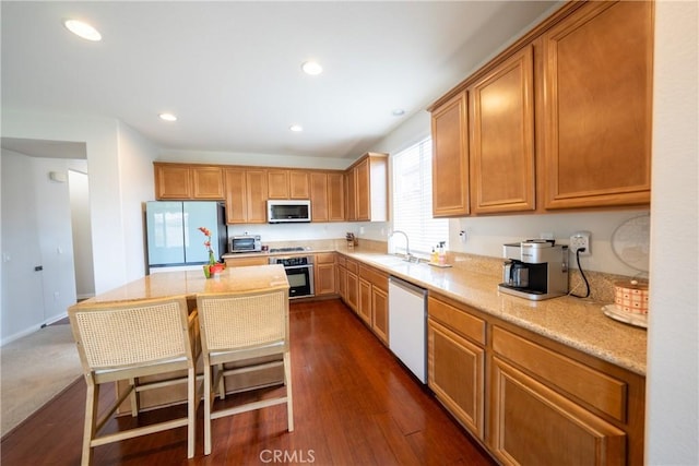 kitchen with appliances with stainless steel finishes, recessed lighting, a sink, and dark wood-style floors