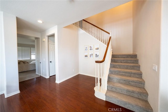 stairs with baseboards, wood finished floors, and recessed lighting