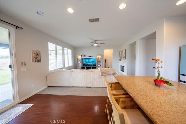 living area featuring a fireplace, visible vents, dark wood finished floors, and recessed lighting