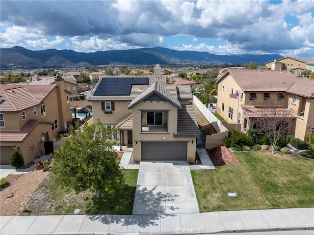 view of front facade featuring stucco siding, concrete driveway, a front yard, a mountain view, and a residential view