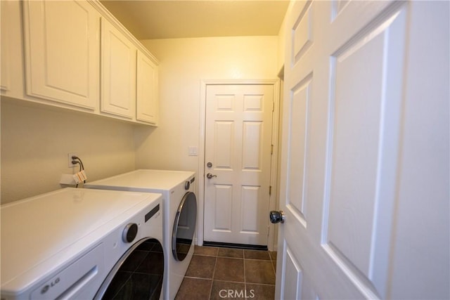 washroom featuring dark tile patterned flooring, washer and clothes dryer, and cabinet space