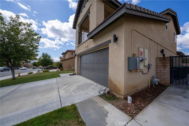 view of home's exterior featuring a garage, a gate, concrete driveway, and stucco siding