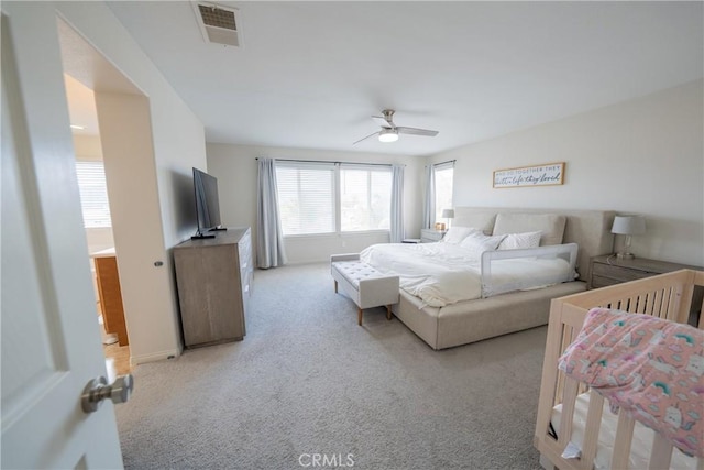 bedroom with light carpet, visible vents, and a ceiling fan