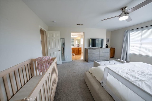 bedroom featuring light carpet, ensuite bath, ceiling fan, and visible vents