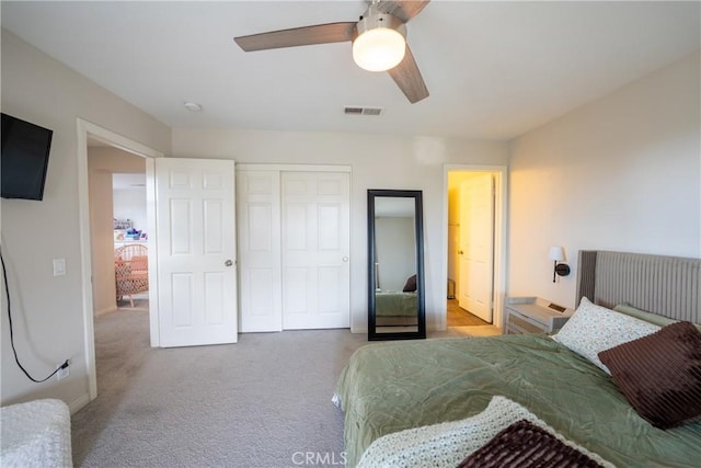 carpeted bedroom featuring a ceiling fan, visible vents, and a closet