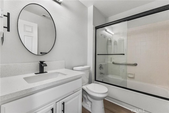 full bath featuring visible vents, toilet, wood finished floors, shower / bath combination with glass door, and vanity