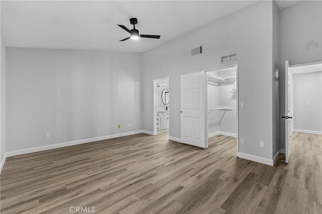 unfurnished bedroom featuring a walk in closet, wood finished floors, visible vents, and baseboards