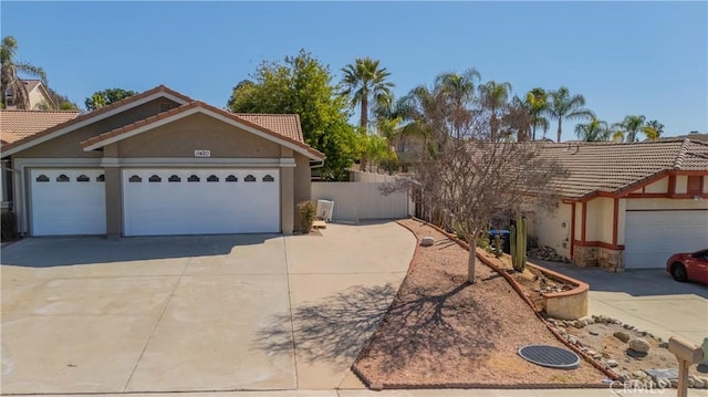 view of front of property with stucco siding, concrete driveway, a tile roof, and fence