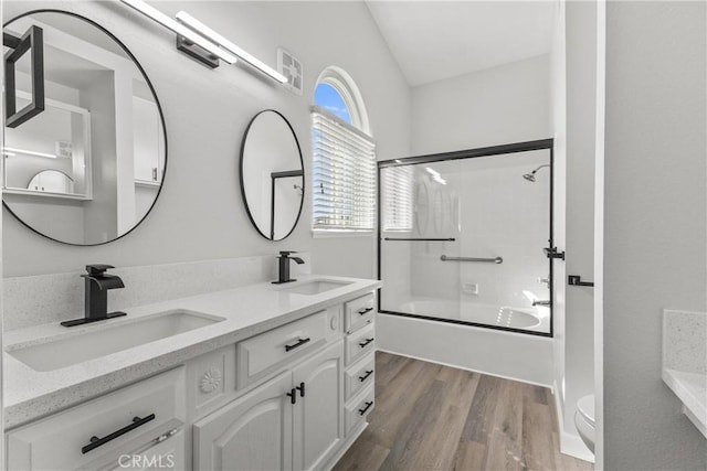 bathroom with double vanity, toilet, wood finished floors, and a sink