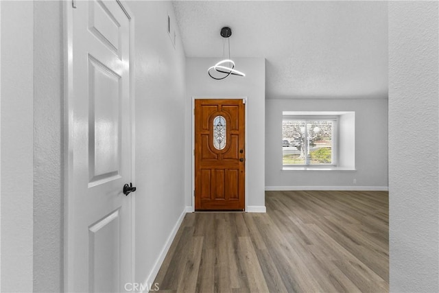 entryway featuring wood finished floors, baseboards, and a textured ceiling