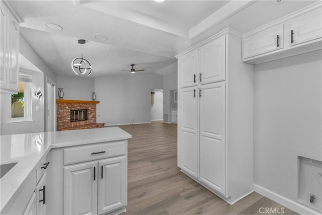 kitchen featuring open floor plan, light wood-type flooring, a peninsula, white cabinets, and a ceiling fan