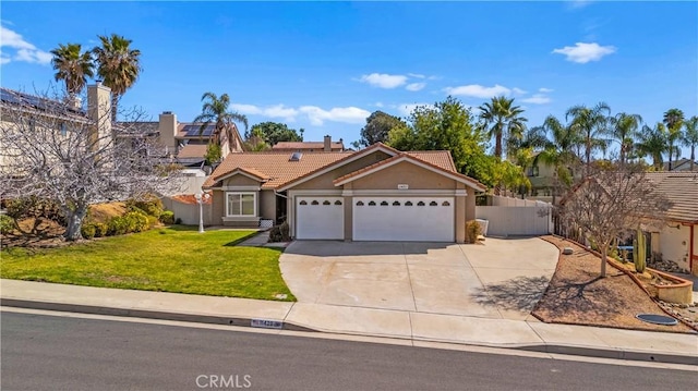 view of front of property featuring a tile roof, fence, concrete driveway, an attached garage, and a front yard