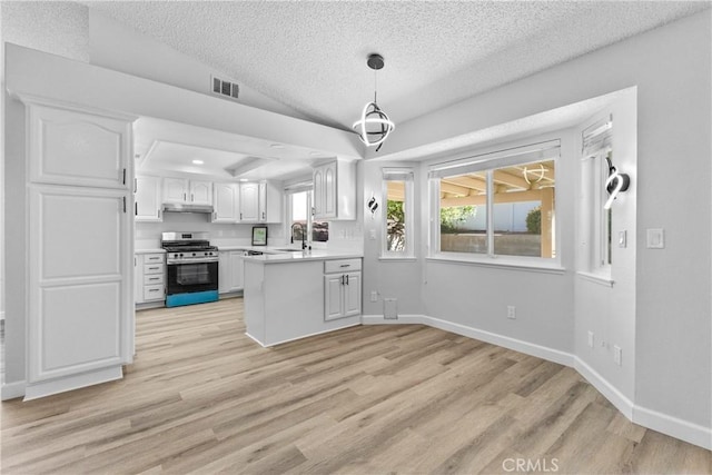 kitchen with stainless steel gas range oven, light wood-style floors, white cabinets, and light countertops