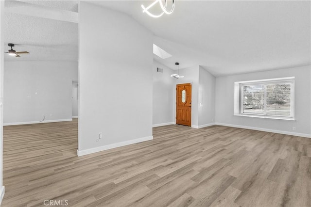 unfurnished living room featuring light wood finished floors, baseboards, lofted ceiling, ceiling fan with notable chandelier, and a textured ceiling