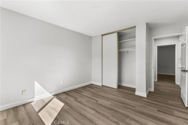 unfurnished bedroom featuring a closet, baseboards, and wood finished floors