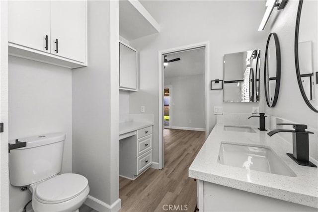 bathroom with double vanity, toilet, wood finished floors, and a sink