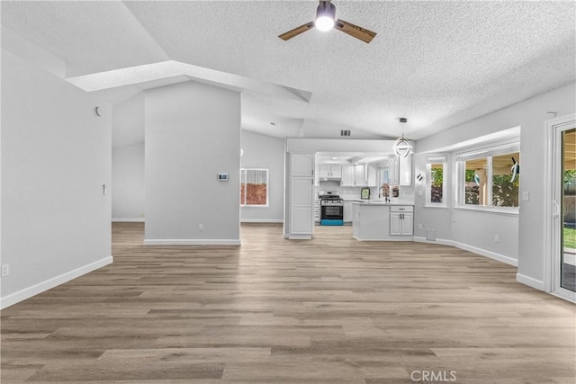 unfurnished living room featuring a sink, light wood-style flooring, ceiling fan, and vaulted ceiling