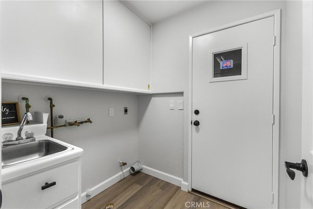 washroom featuring baseboards, hookup for a gas dryer, dark wood-style floors, cabinet space, and a sink