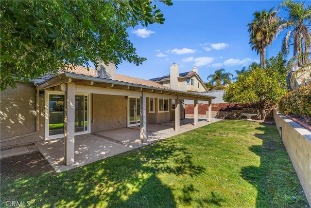 rear view of house featuring a yard, a patio, a fenced backyard, and stucco siding