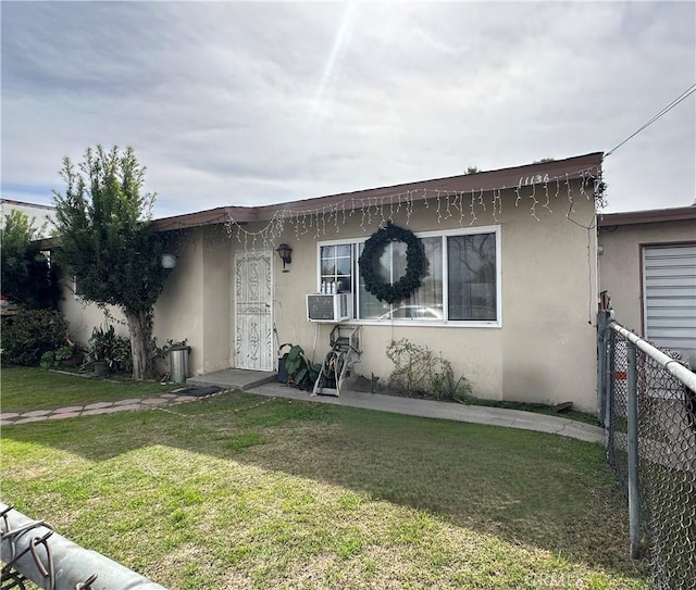 view of front facade with a front lawn, fence, and stucco siding