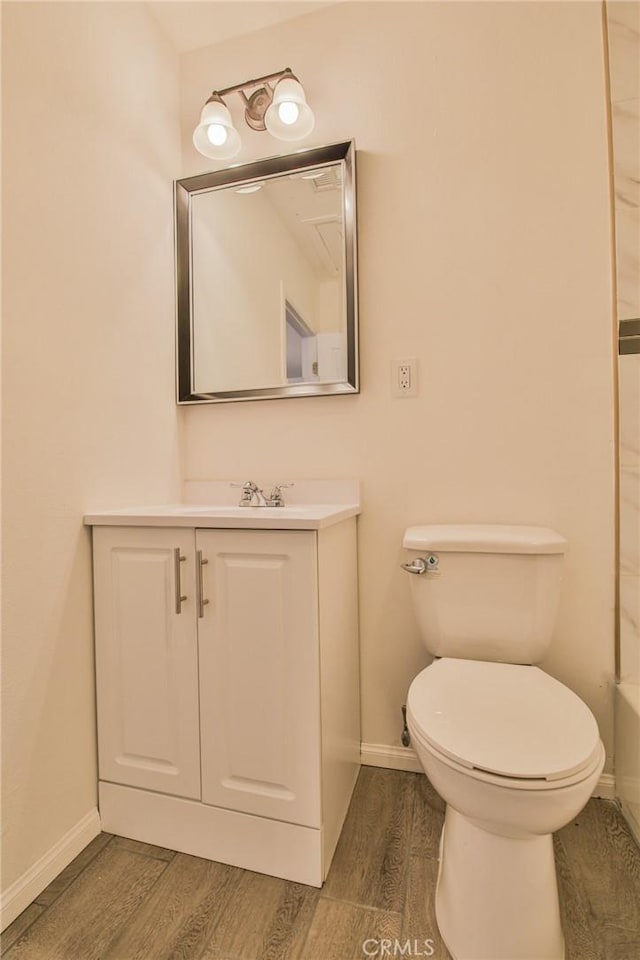 bathroom featuring toilet, wood finished floors, vanity, and baseboards