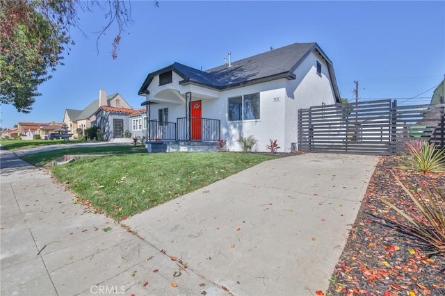 bungalow-style house with a gate, fence, a front lawn, and stucco siding