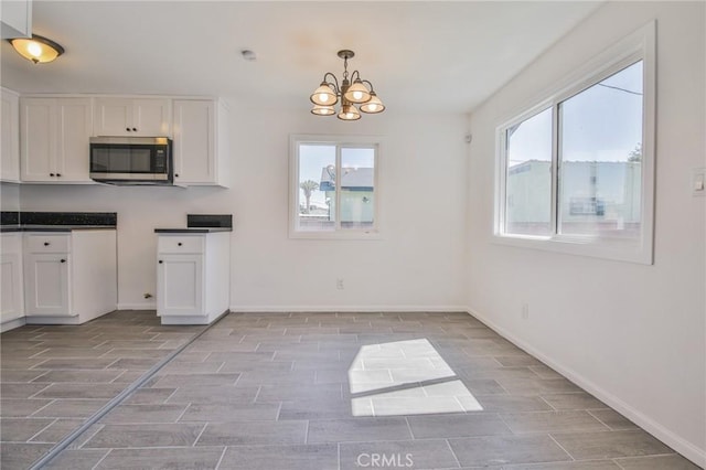 kitchen featuring wood tiled floor, stainless steel microwave, white cabinets, and a wealth of natural light