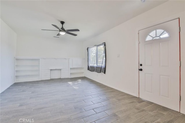 unfurnished living room with ceiling fan, a fireplace, and wood finished floors