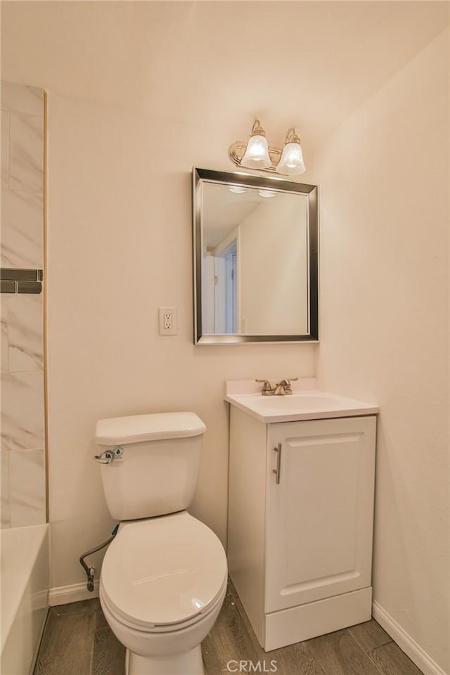 full bathroom with a washtub, toilet, vanity, wood finished floors, and baseboards