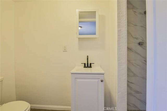 bathroom with a shower, baseboards, vanity, and toilet