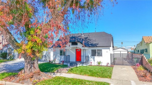 view of front facade featuring stucco siding, fence, concrete driveway, and a front yard