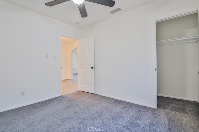 unfurnished bedroom featuring arched walkways, carpet flooring, visible vents, baseboards, and a closet