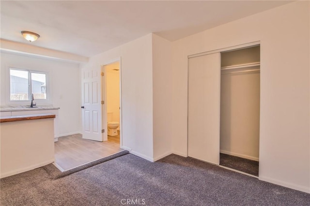 unfurnished bedroom with a closet, baseboards, and carpet flooring