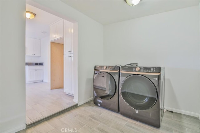 washroom featuring laundry area, light wood finished floors, baseboards, and separate washer and dryer