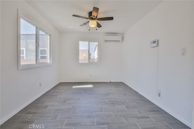 empty room featuring a wealth of natural light, a wall mounted air conditioner, baseboards, and wood tiled floor