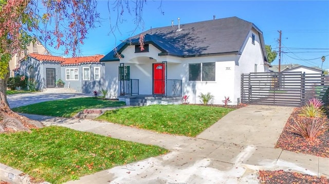 view of front of property with a gate, fence, a front lawn, and stucco siding