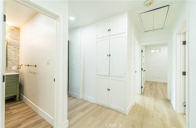 hallway with attic access, light wood-style floors, and baseboards