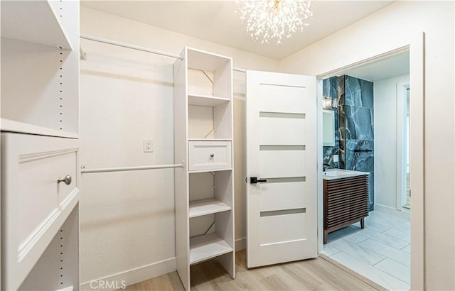 spacious closet featuring an inviting chandelier and light wood finished floors