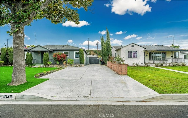 view of front facade with stucco siding, a gate, concrete driveway, and a front yard