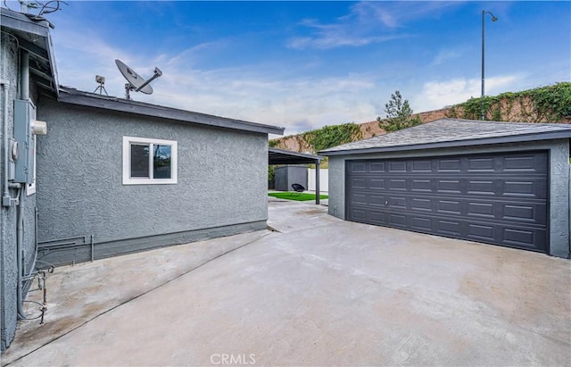 view of side of home featuring an outbuilding, a detached garage, and stucco siding