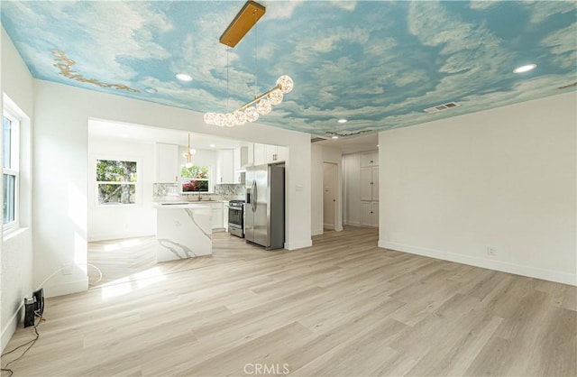 unfurnished living room with baseboards, visible vents, and light wood-style floors