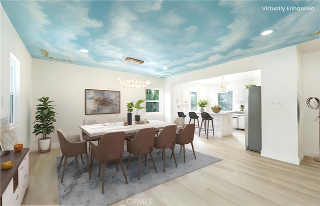 dining room with light wood-type flooring, a notable chandelier, and baseboards