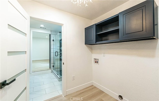 washroom featuring washer hookup, cabinet space, light wood-style flooring, and baseboards