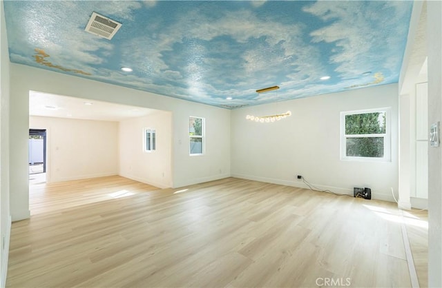 unfurnished room featuring light wood-type flooring, baseboards, and visible vents