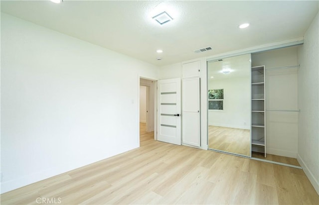 unfurnished bedroom featuring light wood finished floors, a closet, visible vents, and baseboards